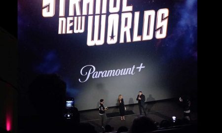 Paramount+ Launch Party. Dunkler Kinosaal, Logo von Star Trek auf der Leinwand, Anson Mount mit Mikrofon im Spotlight
